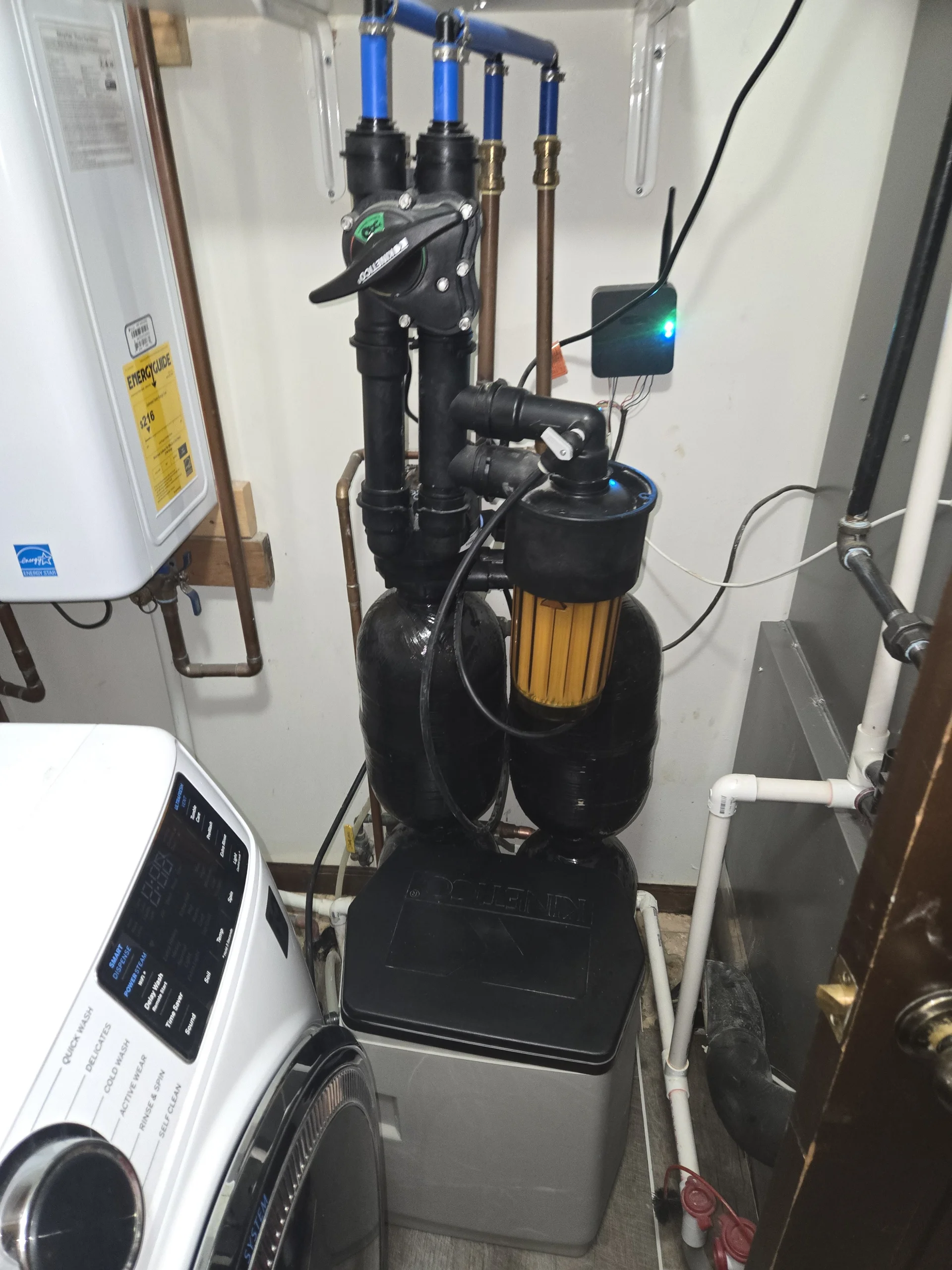 A professional residential water softener system installed inside a tight home utility room.