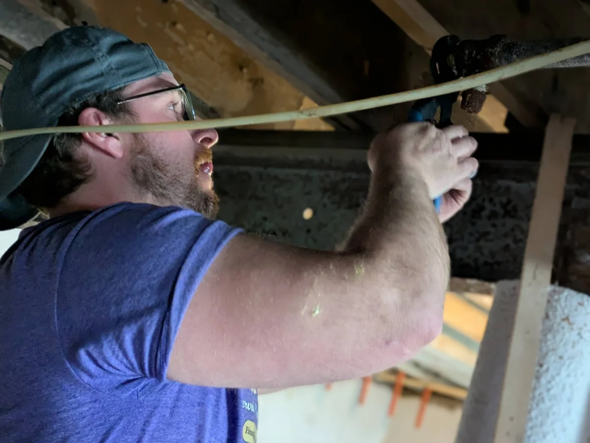 Professional plumbers neatly installing flexible high-quality water supply lines along basement joists.
