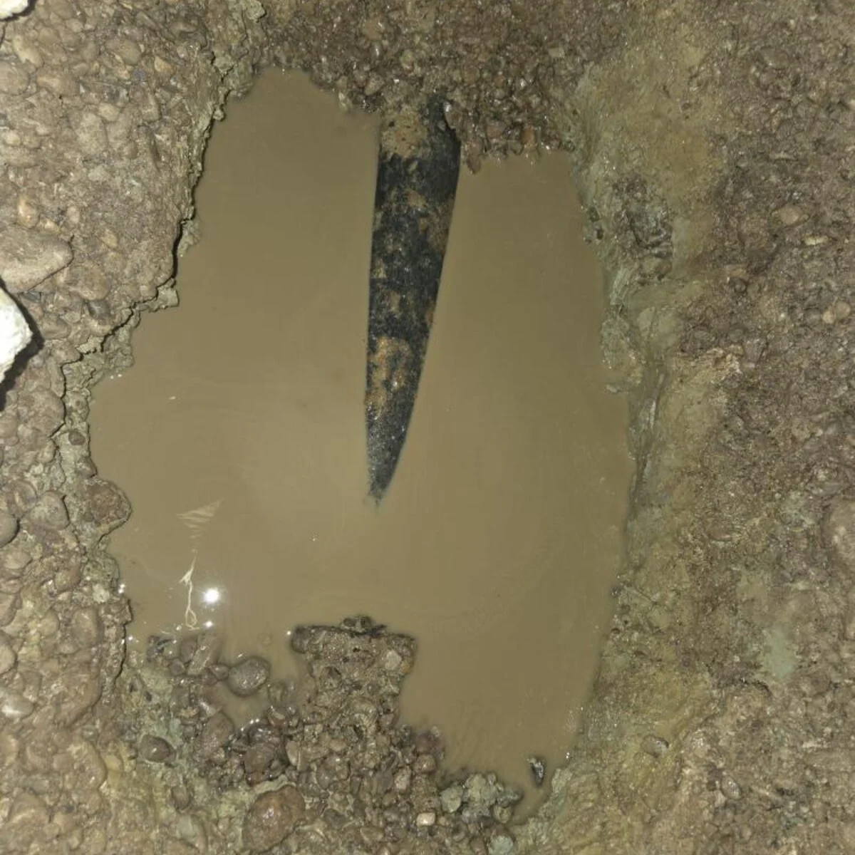 Old drain line under a basement slab sitting in water before a backwater valve installation in Centerville, Ohio