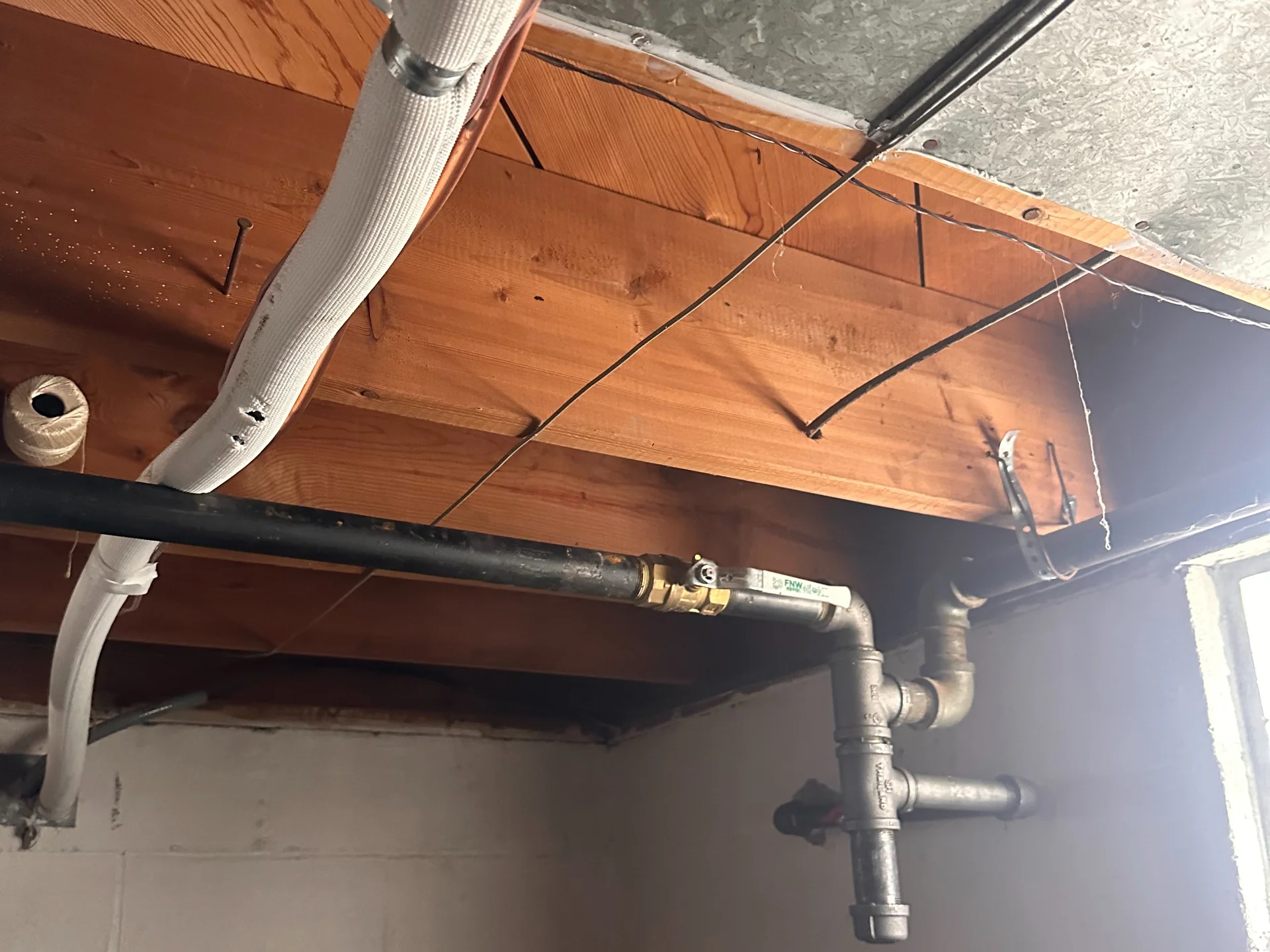 Basement gas line with a brass shutoff valve running along ceiling joists in a Dayton-area home, tested fitting by fitting for leaks